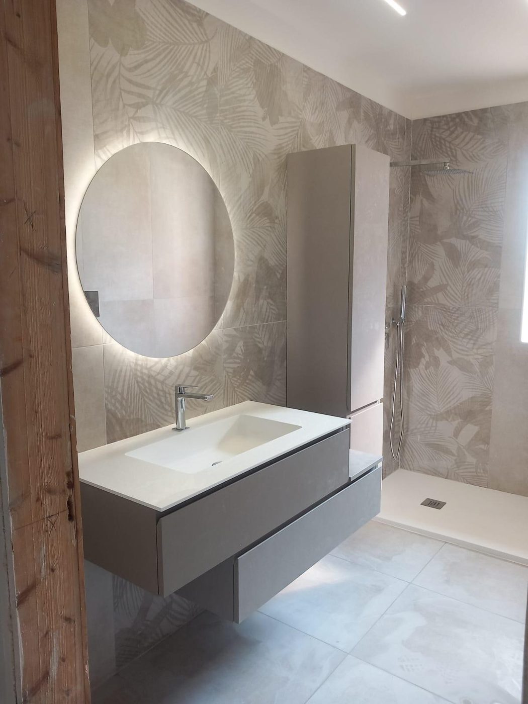 Bagno effetto marmo con specchio LED tondo e mobile sospeso