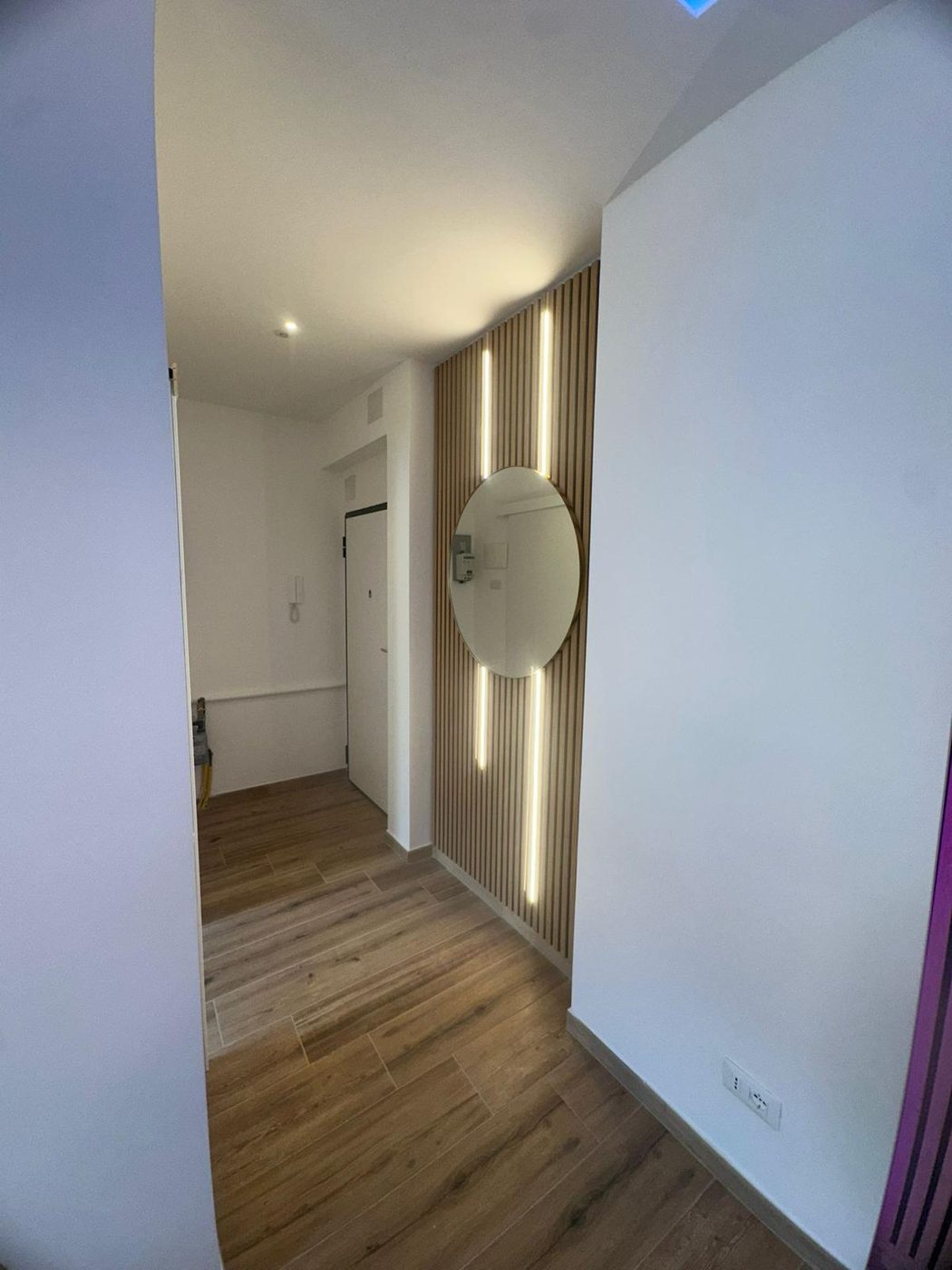 Corridoio con luci LED lineari e pavimento in parquet